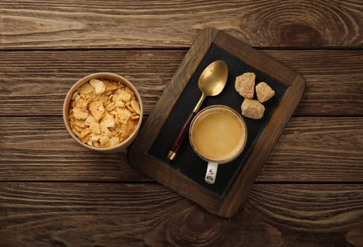 Close up glass cup of espresso coffee and Napoleon mille-feuille vanilla custard slice cake, on black slate over wooden table, high angle view