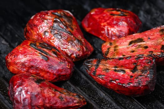 Close up cooking fresh new red beet roots in outdoor charcoal grill with cast iron metal grate, high angle view