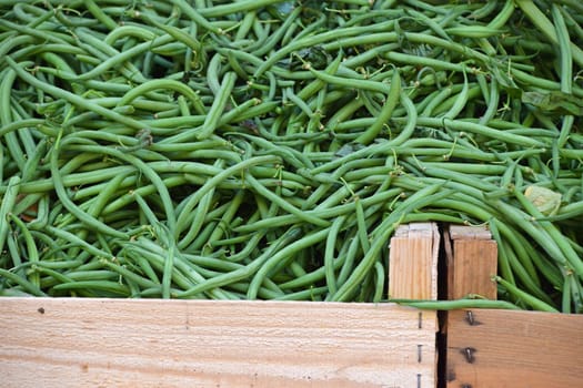 Heap of fresh green been on retail display of farmers market, close up, high angle view