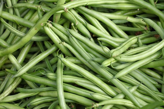 Heap of fresh green been on retail display of farmers market, close up, high angle view