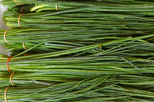 Bunch of fresh green spring bunch onion, scallion or chive on farmers market display, close up, high angle view