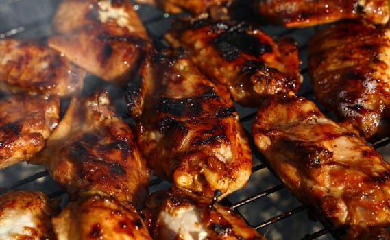 Close up cooking and smoking chicken buffalo or teriyaki sauce wings on bbq char grill, high angle view