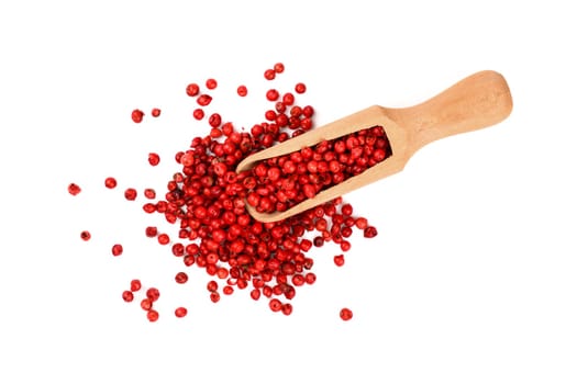 Close up one wooden scoop full of red pink pepper peppercorns spilled and spread around isolated on white background, elevated top view, directly above