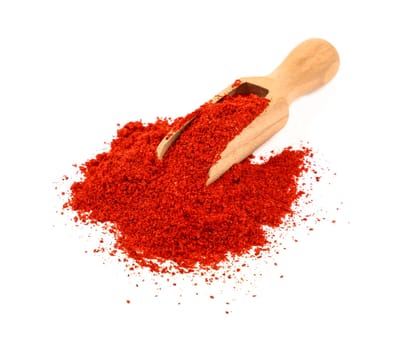 Close up one wooden scoop full of red chili pepper, paprika or sundried tomato powder spilled and spread around isolated on white background, high angle view