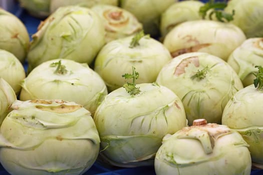 Close up many fresh green kohlrabi cabbages (German turnip) at retail display of farmer market, high angle view