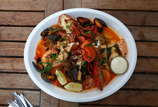 Close up large grilled seafood platter on wooden table, high angle view