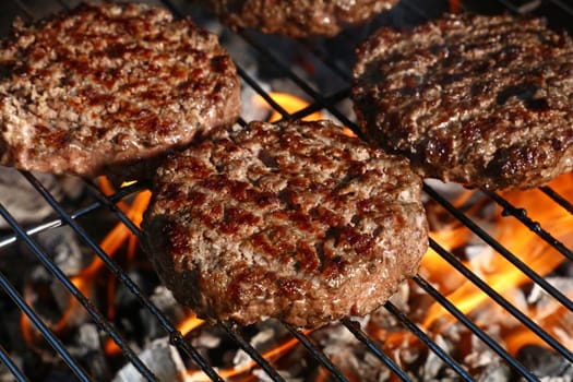 Close up beef or pork meat barbecue burgers for hamburger prepared grilled on bbq fire flame grill, high angle view