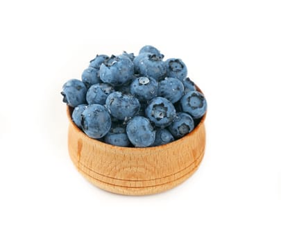 Portion of fresh washed blueberry berries in rustic wooden bowl, wet with water drops, isolated on white background, high angle view