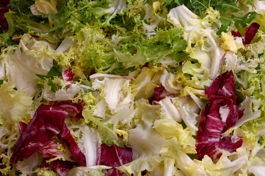 Heap of fresh mixed green and red lettuce salad on farmers market display, close up, high angle view