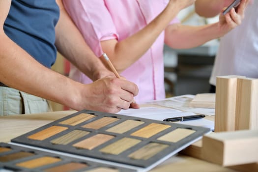 Close up work in carpentry furniture workshop, hands of workers, wooden furniture palette.