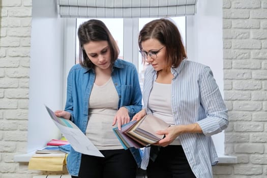 Two women interior designer and client choosing fabrics for home textile decoration, curtains, furniture upholstery