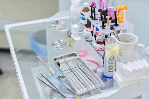Kyiv UA, 31-07-2019. Close-up of working desk in dentist office with dental composite sealing materials resins, various professional dental instruments tools and medicines