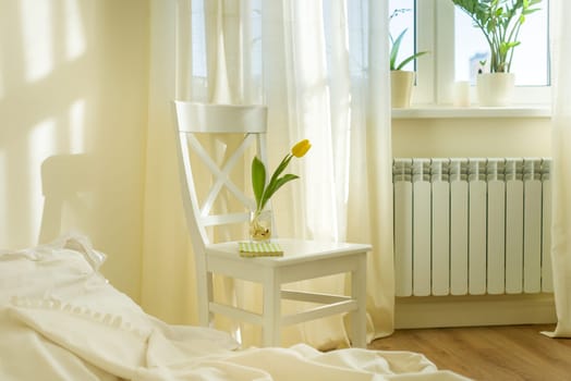 Light spring bedroom interior, bed, white chair, glass with yellow tulip, window light curtains, pastel colors