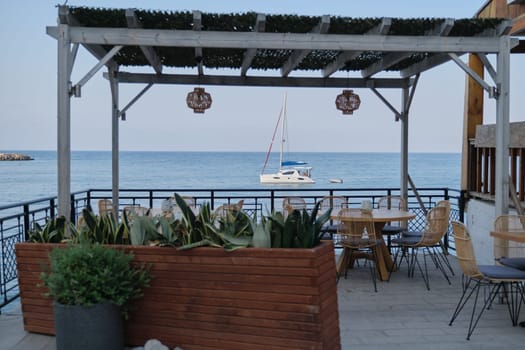 Greece, Crete, Heraklion. 12-09-2019. Greek coast, Mediterranean, empty small cafe by the sea white yacht with vacationers