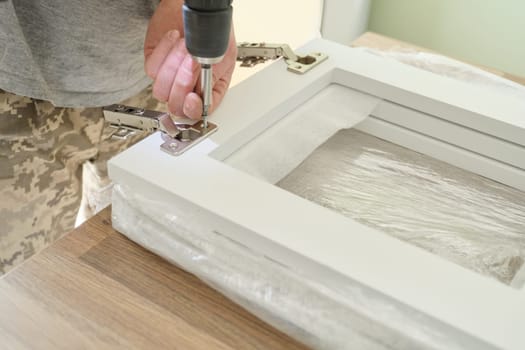 Closeup of hand worker doing furniture, assembling kitchen with professional tools