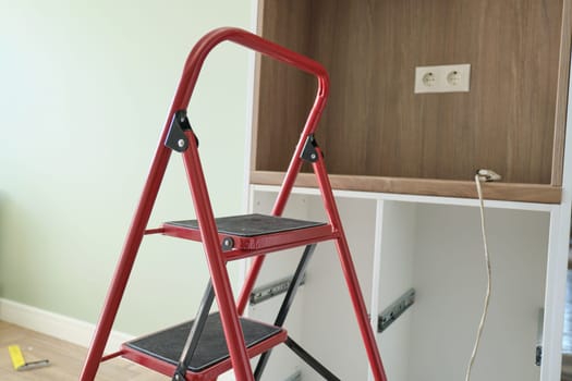 Concept of repair, manufacturing and installation of furniture, stepladder in interior.