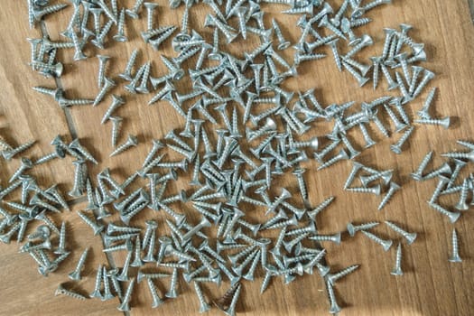 Chrome screws scattered on the floor, repair concept, furniture manufacturing. Abstract industrial background