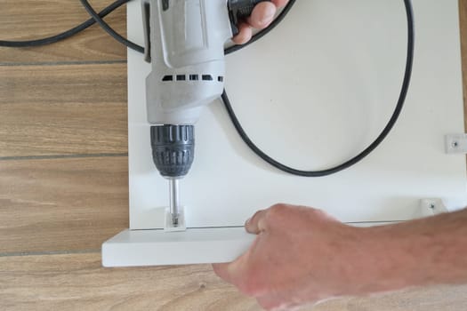 Closeup of hand worker doing furniture, assembling kitchen with professional tools