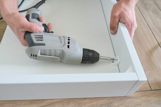 Furniture assembly. Closeup of workers hand with professional tools and furniture details