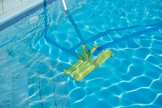 Close-up of outdoor swimming pool underwater, cleaning vacuum tube.