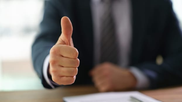 Businessman showing thumb up at work in office closeup. successful business people concept