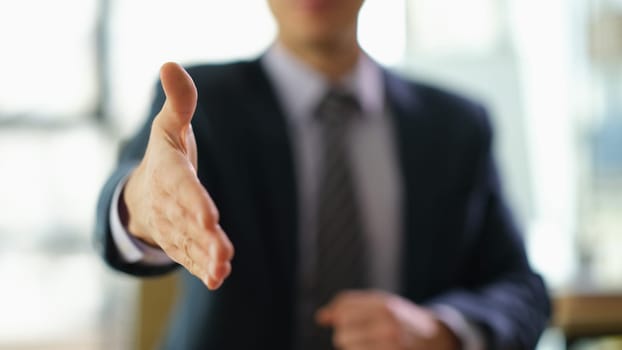 Businessman in suit extending his hand for handshake to partner at work in office closeup. Successful customer service concept