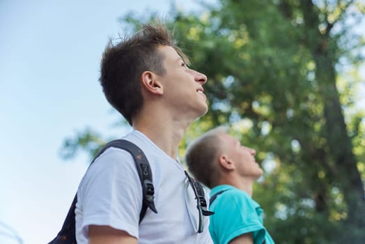 Outdoor portrait of smiling handsome young males, two laughing teenagers looking up