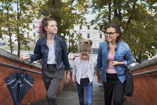 Mother and children two daughters walking on the stairs in autumn city