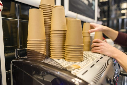 Brown kraft paper coffee cups on coffee machine in coffee shop interior.