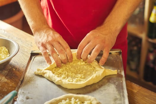 Healthy natural food, hands of man preparing khachapuri, on the table flour dough cheese. Cooking process, culinary, recipe, home bakery.