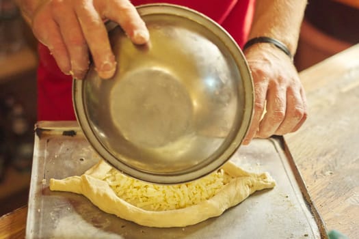 Healthy natural food, hands of man preparing khachapuri, on the table flour dough cheese. Cooking process, culinary, recipe, home bakery.