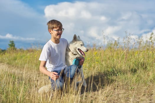 Boy with white dog, teenager walking with husky pet, background landscape with cloudy sky, yellow burnt grass