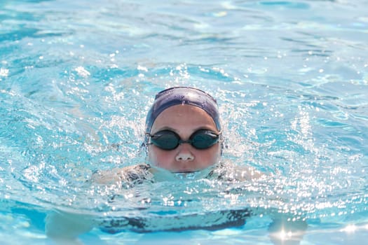 Face of young women swimmer in pool, girl in cap goggles for swimming. Active sports healthy lifestyle of youth