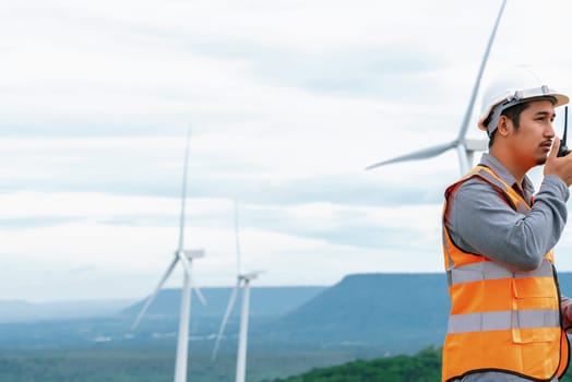 Engineer working on a wind farm atop a hill or mountain in the rural. Progressive ideal for the future production of renewable, sustainable energy. Energy generation from wind turbine.