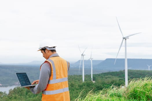 Engineer working on a wind farm atop a hill or mountain in the rural. Progressive ideal for the future production of renewable, sustainable energy. Energy generation from wind turbine.