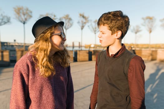 Outdoor portrait of a couple of young boy and girls looking at each other, smiling teenagers in the sunset light, golden hour