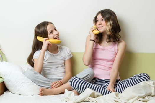 Connection, communication between people, girls play phone, talk with each other through a banana pipe.