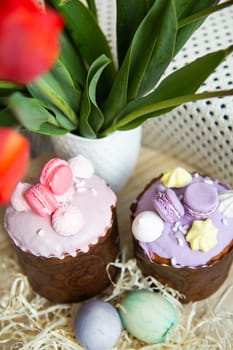 Colorful Easter eggs lie together with Easter pastries decorated with colored chocolate on a wooden table. Easter holiday