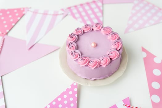 Delicate lavender pink bento cake on a plate against a background of flags for a party. Celebration, happy day