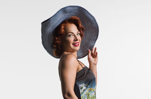 Portrait of a mature woman with red hair and a hat. Photo taken in studio on a white background.