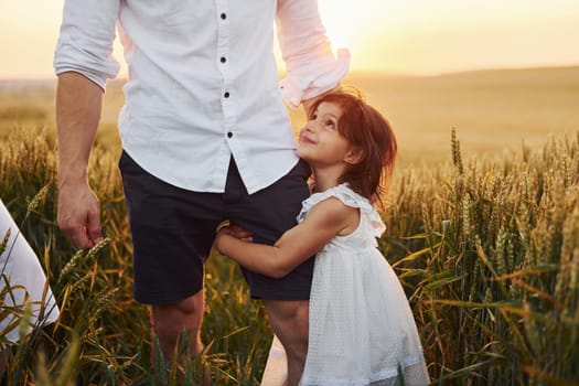 Girl embraces parent. Father with daughter spending free time on the field at sunny day time of summer.