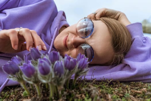 Dream grass woman spring flower. Woman lies on the ground and hugs flowers pasqueflower or Pulsatilla Grandis flowers.
