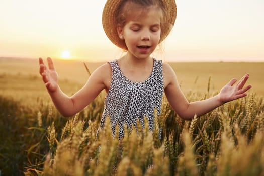 Little girl standing on the agricultural field at evening time. Conception of summer free time.