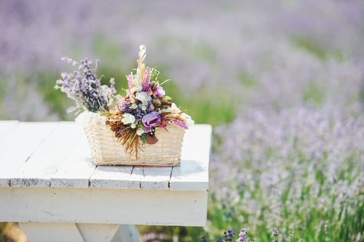 Close up view of bouquet of lavender flowers in basket that lying on the white table in field.