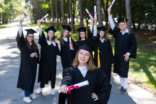 Happy young caucasian woman celebrating graduation with classmates. A group of graduate students outdoors