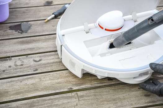 woman washing a trash can in a robot vacuum cleaner,planned maintenance of equipment for long-term use, High quality photo