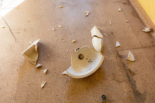 A broken old sink lying on the floor in a room of an old abandoned hospital