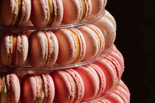 Sweet pyramid of the french macarons or macaroon for the birthday, event or wedding on black background. selective focus. copy space