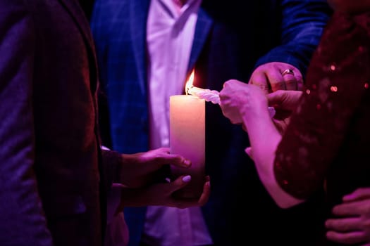 Happy stylish wedding couple holding candles with fire and light them up with candle from parents, family fire tradition at reception. Bride and groom at holy matrimony.