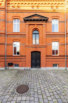 The front of a renovated tall brick building with large black doors